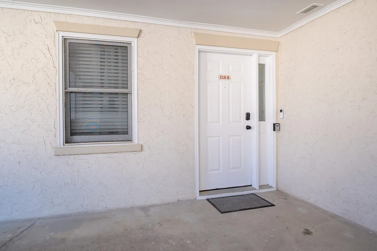 This image showcases the exterior of the property, focusing on the welcoming front door and window, set in a cozy, inviting atmosphere. The scene evokes first impressions and hints at coming together, perhaps after a day spent at the nearby beach or local attractions.