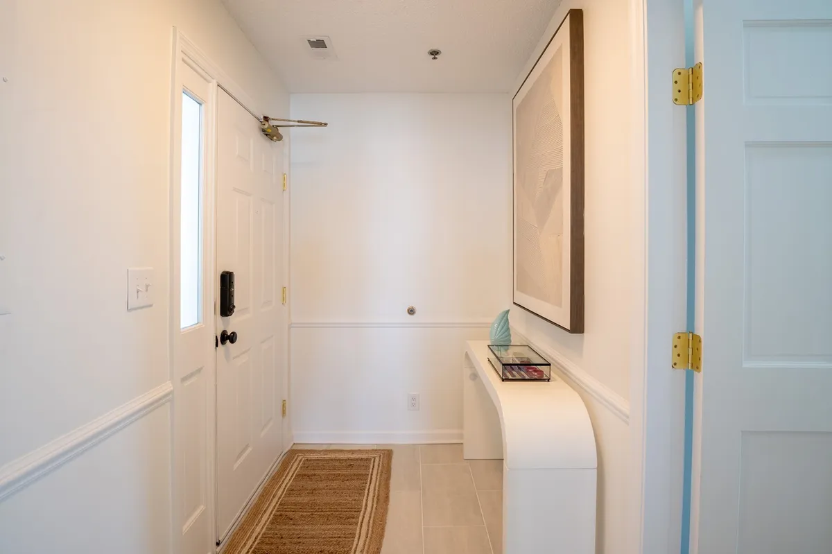 A welcoming entryway showcasing the front door, a piece of artwork, a console table, and a doormat. The space sets the tone for arrival and the excitement of a getaway shared with friends.